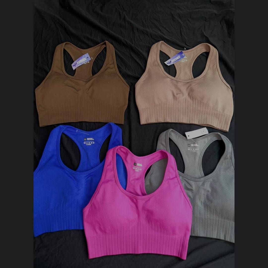 Cinco sujetadores deportivos con espalda cruzada de colores: marrón, tostado, azul, rosa y gris.