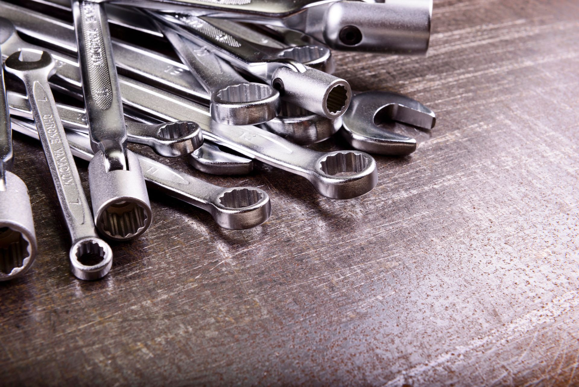 Pila de llaves inglesas y enchufes de metal sobre una superficie gris texturizada.