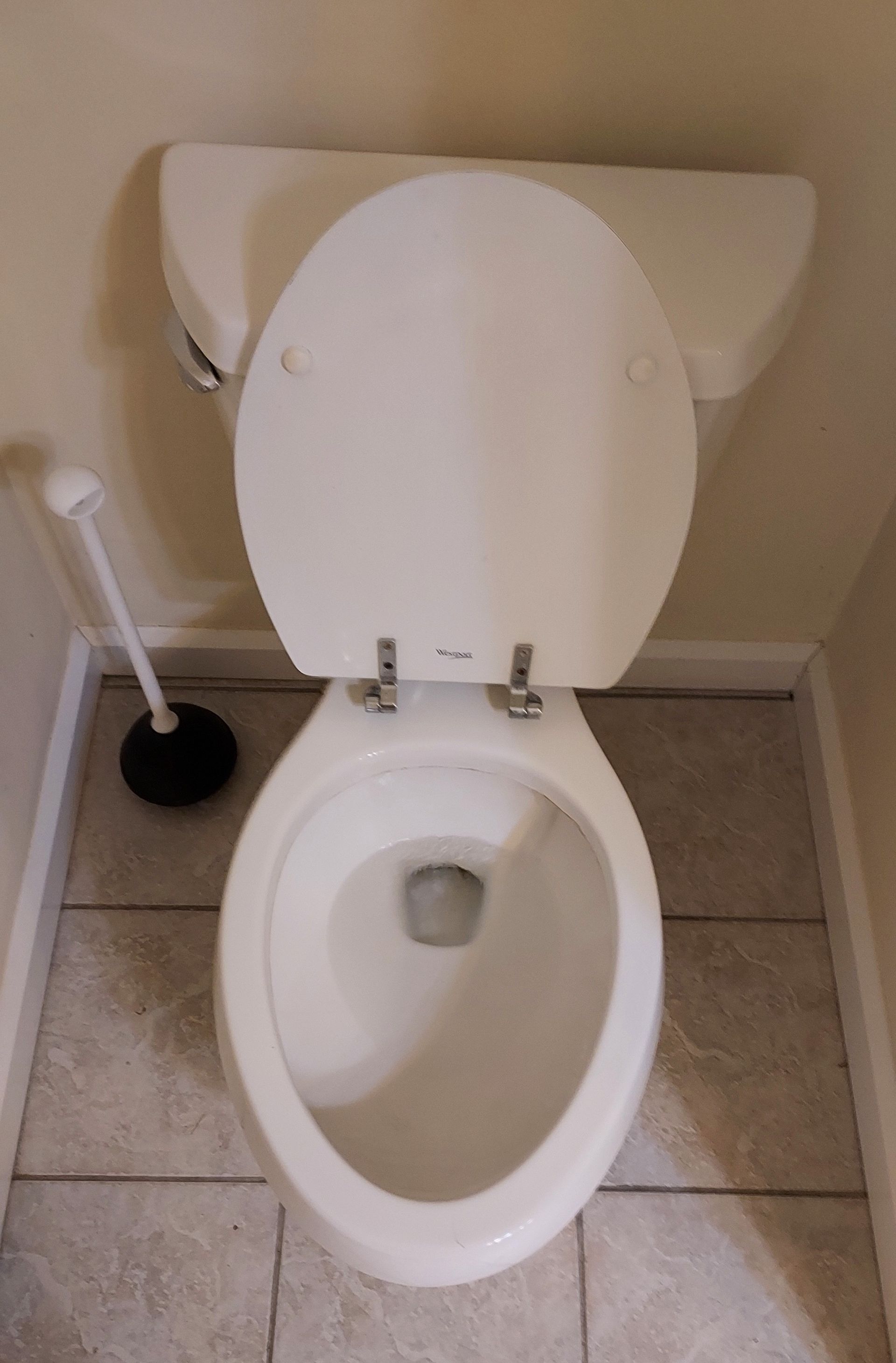 Toilet with open lid and plunger in a bathroom.