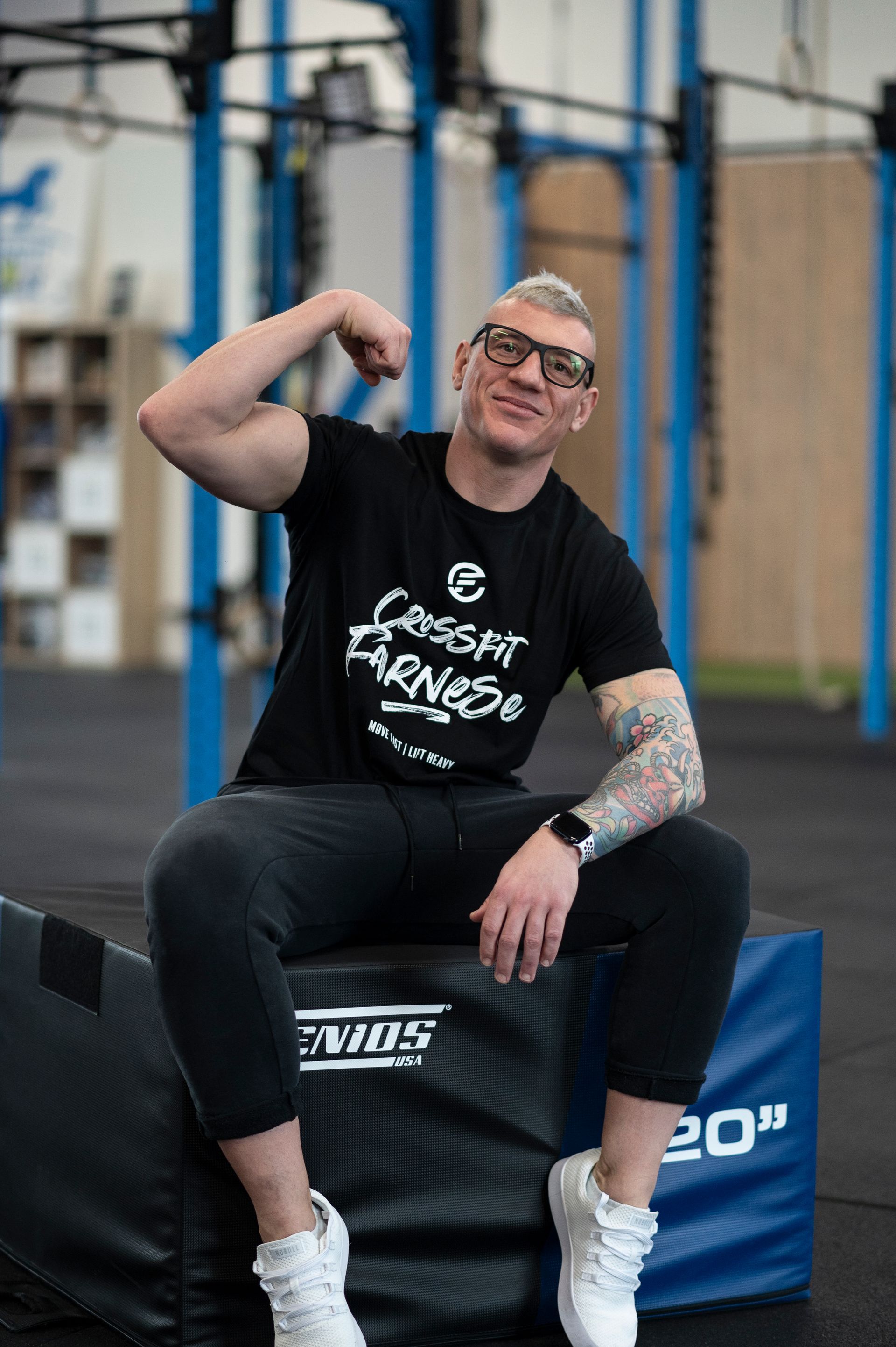 A man in a blue shirt is holding gymnastic rings in a gym.