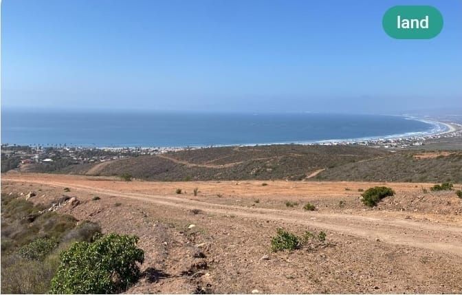Scenic view of land overlooking a coastline, with a clear blue sky.