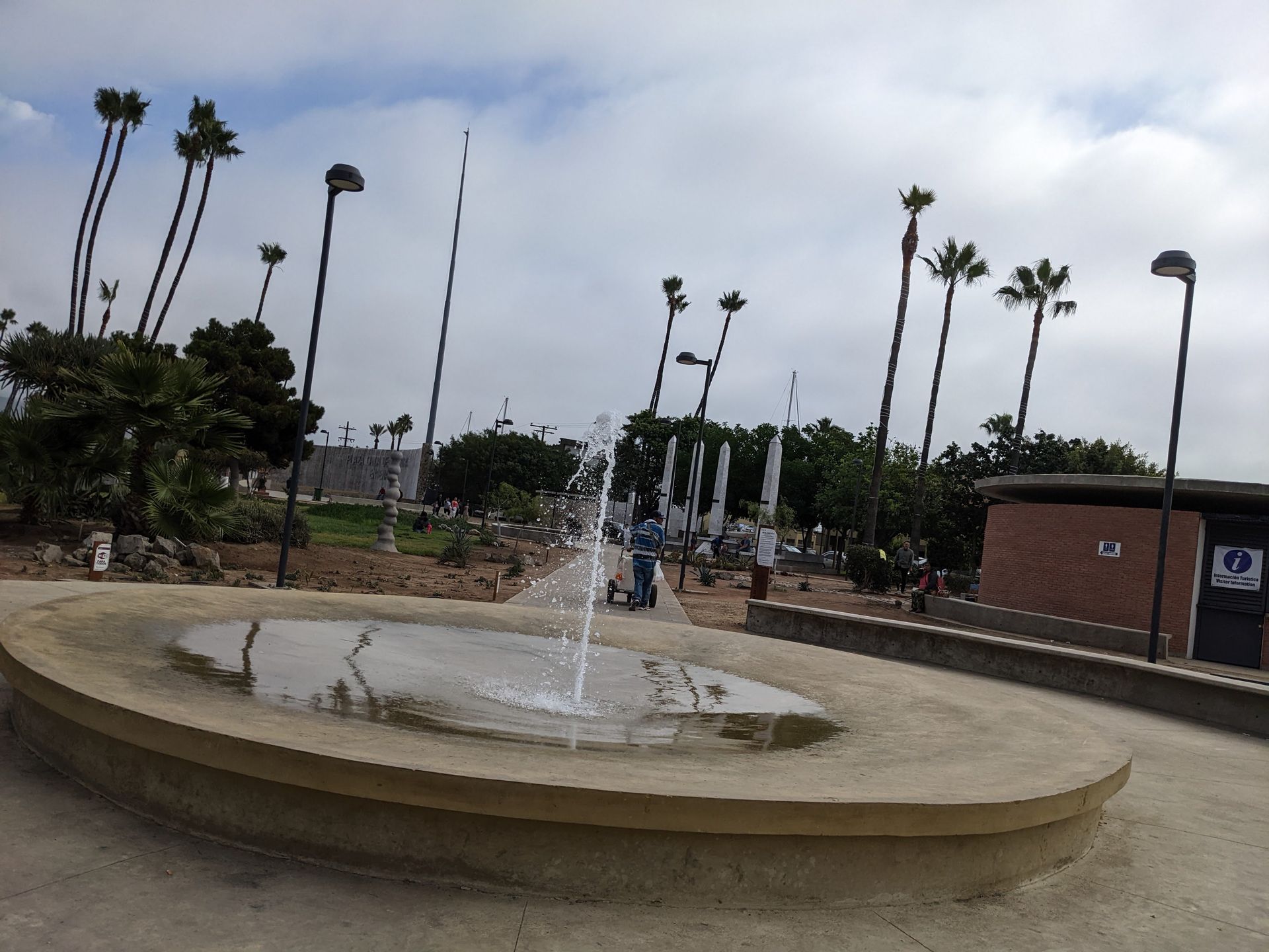 Fountain by cruise ship port, palm trees, park setting.