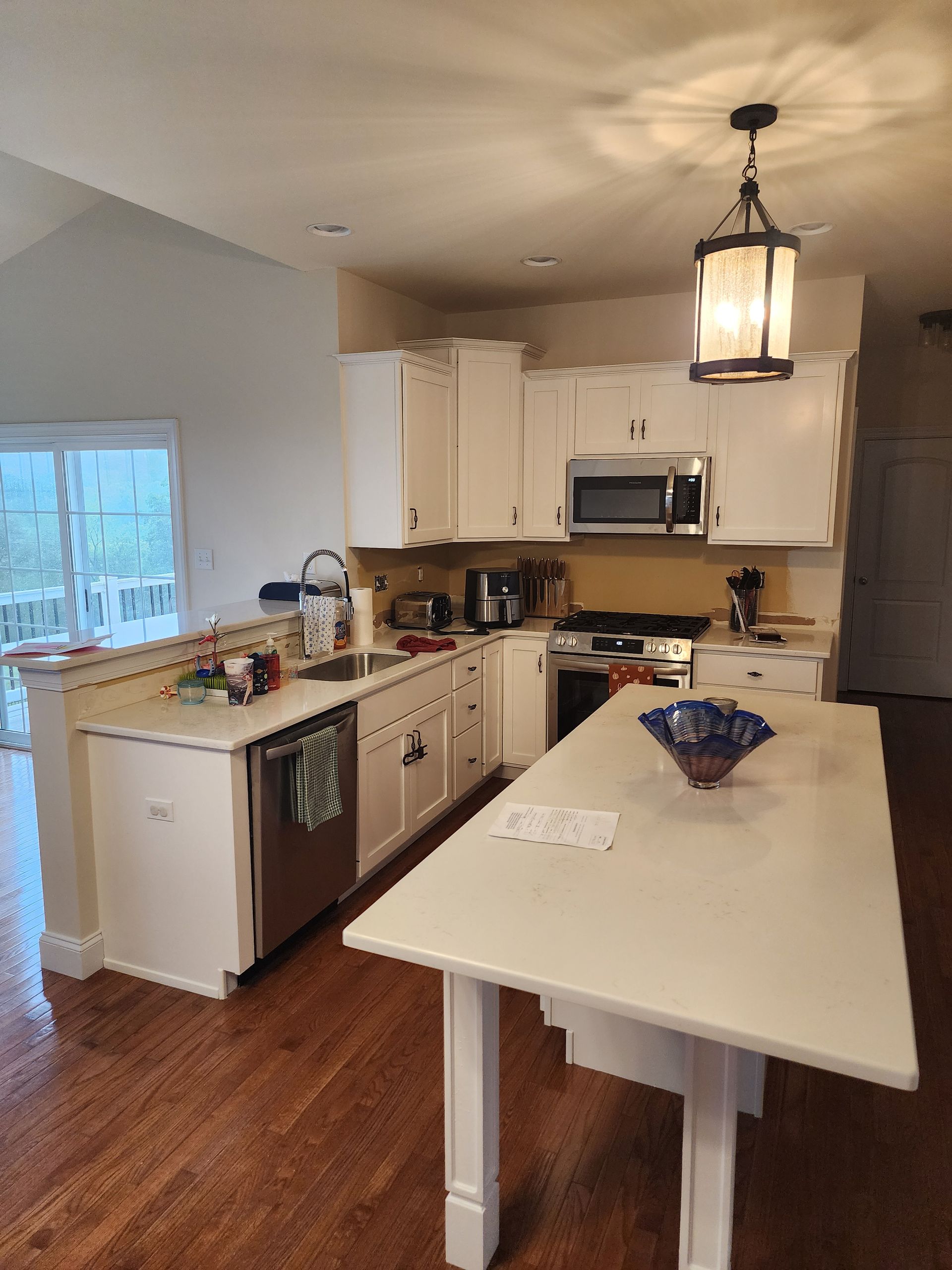 Modern kitchen with white cabinets, island, hanging light, and hardwood floors