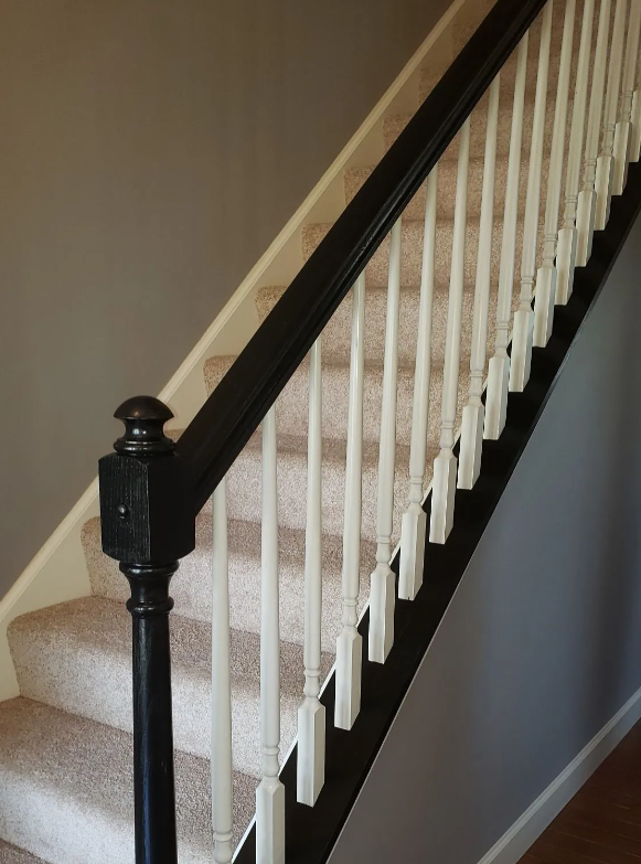Carpeted staircase with dark wood banister and white balusters along a gray wall