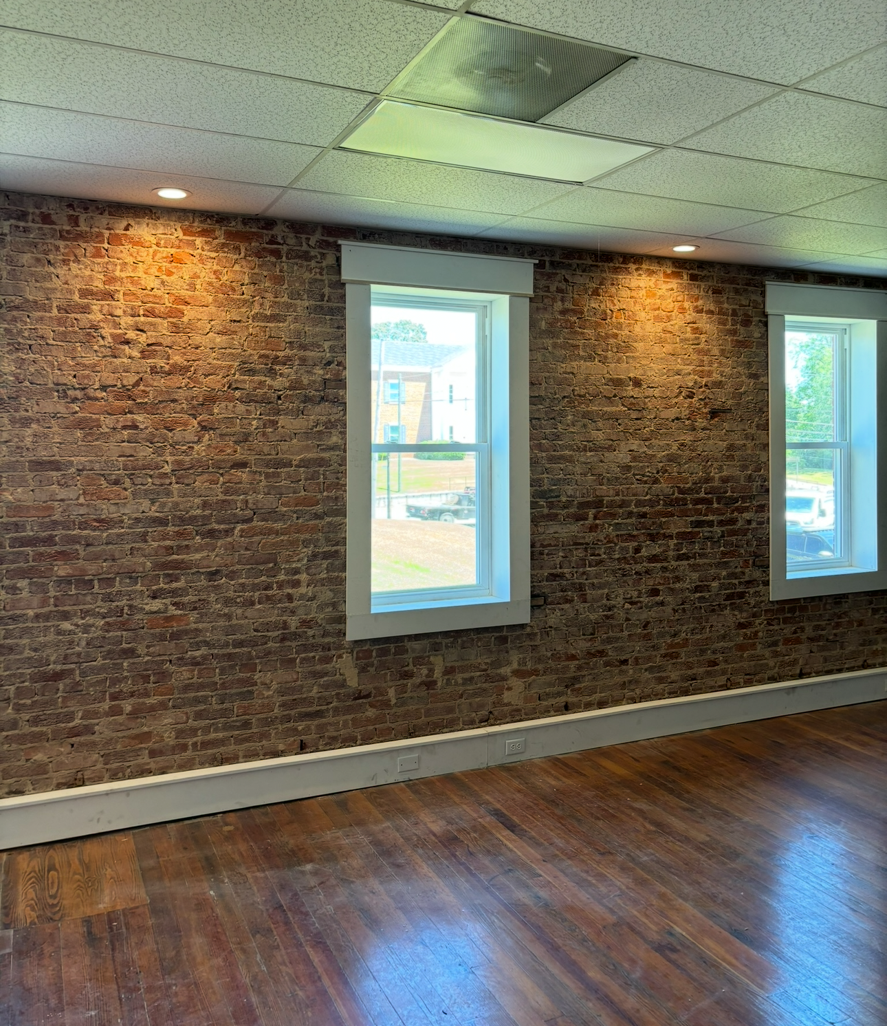 An empty room with a brick wall and three windows
