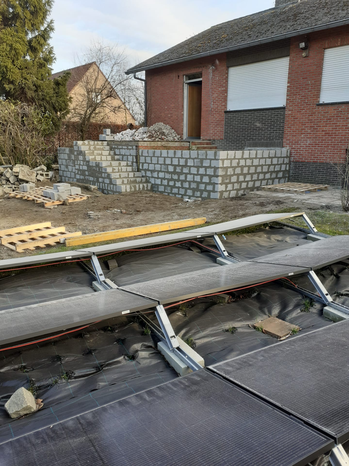 Voor een huis wordt een bakstenen muur gebouwd.