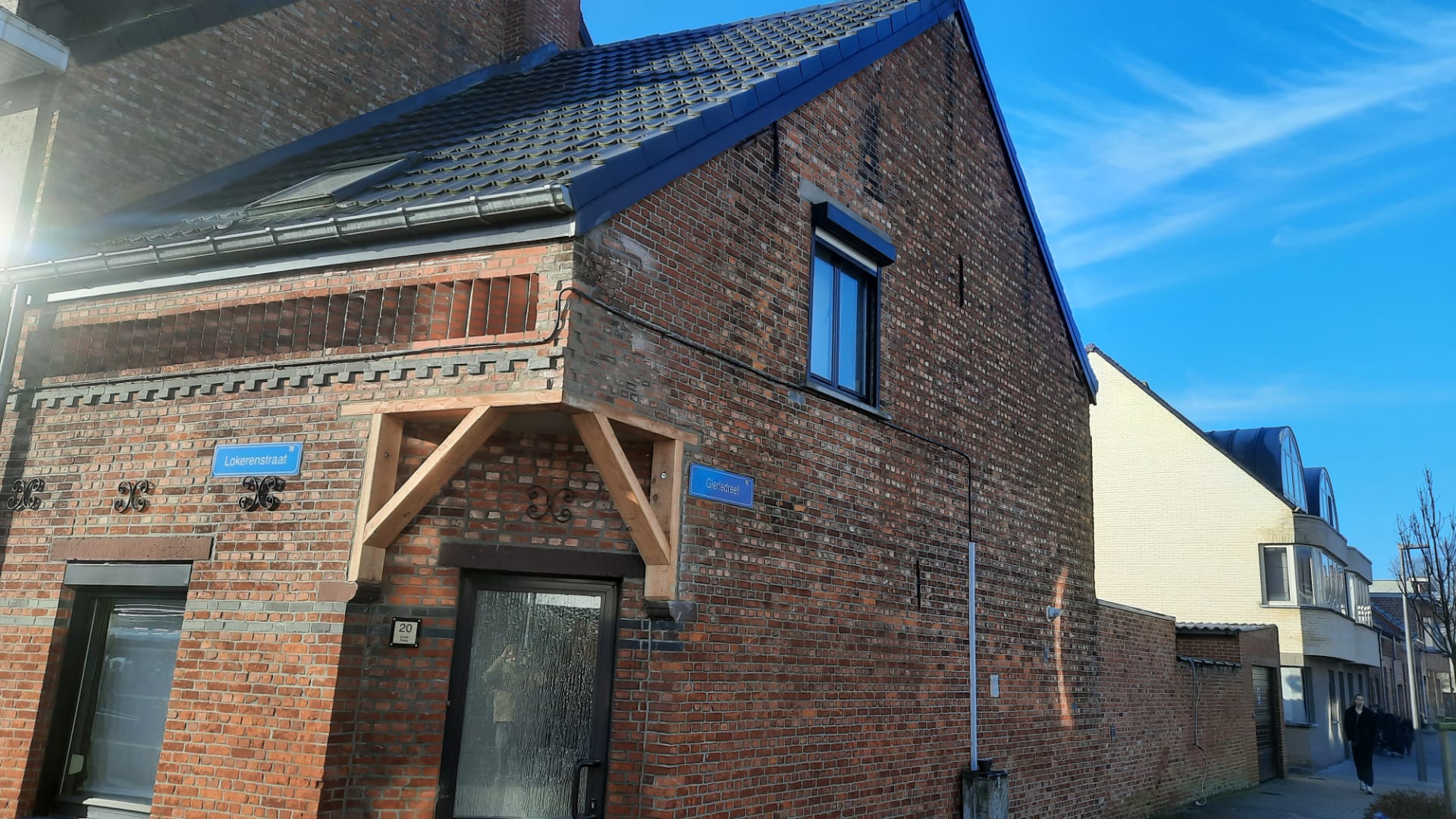 Een bakstenen huis met een houten luifel boven de voordeur.