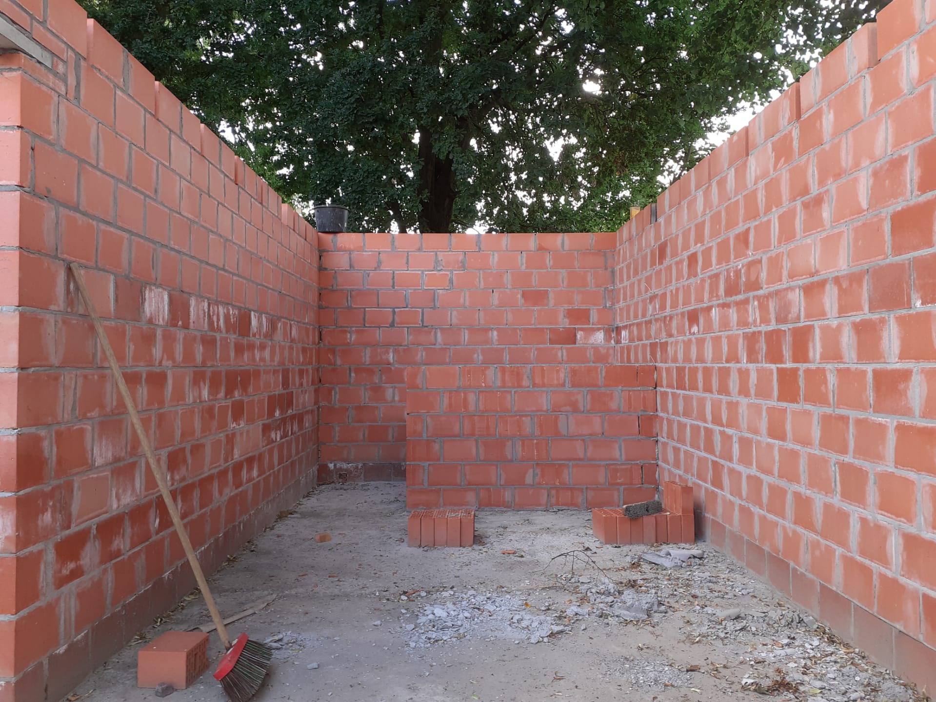 Een bakstenen muur met in het midden een bezem