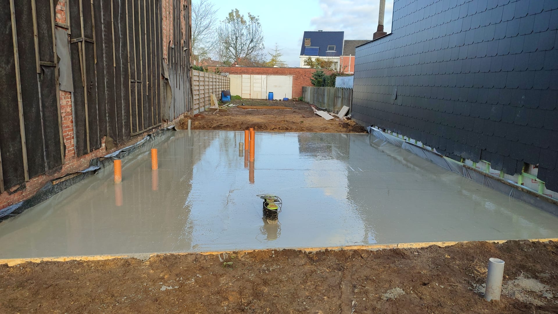 Op een erf voor een gebouw wordt een betonnen vloer gestort.