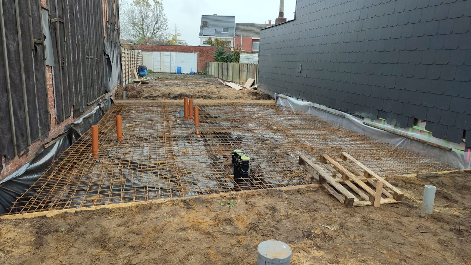 Een bouwplaats met een zwart gebouw op de achtergrond.