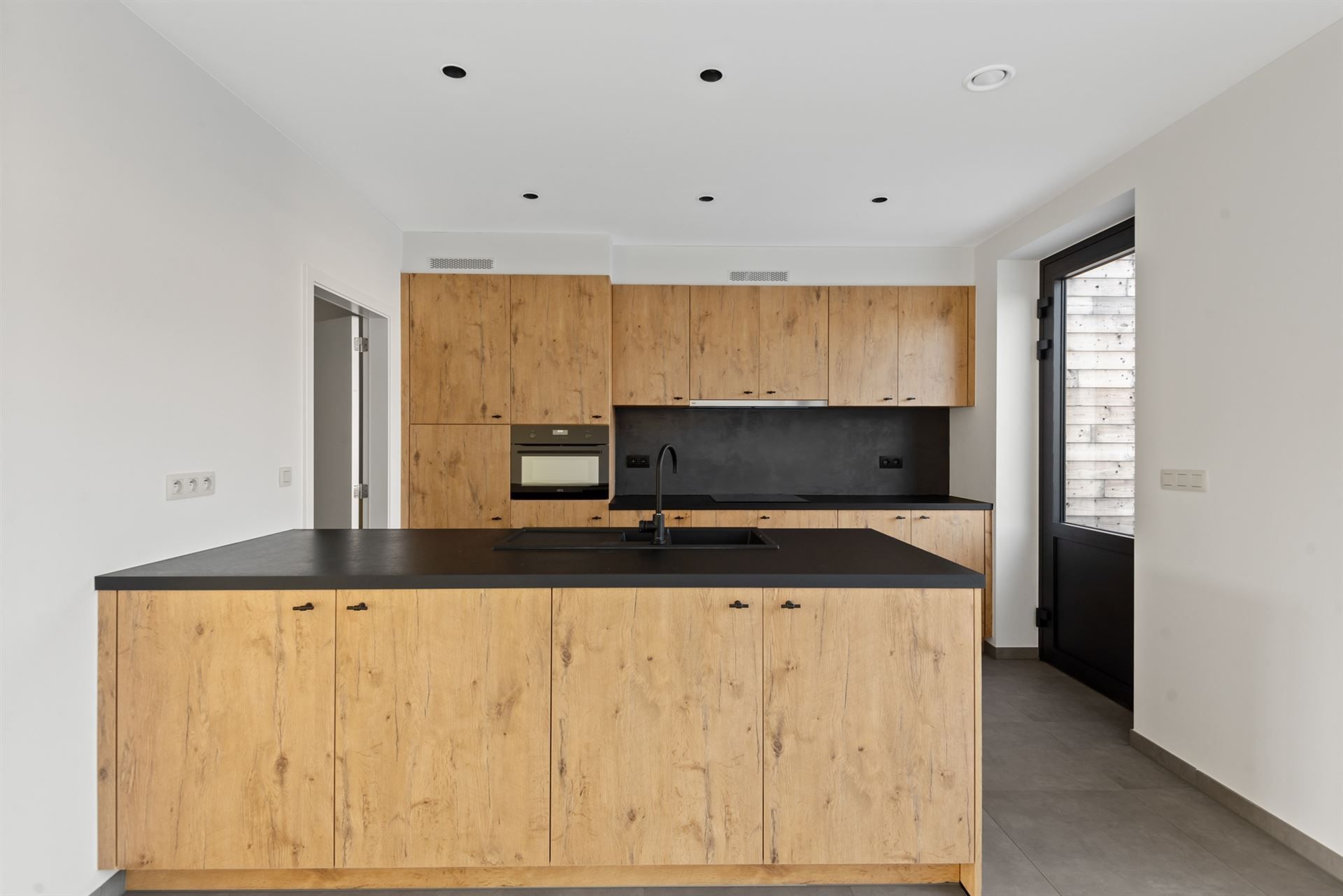 Een keuken met houten kasten en een zwart aanrechtblad