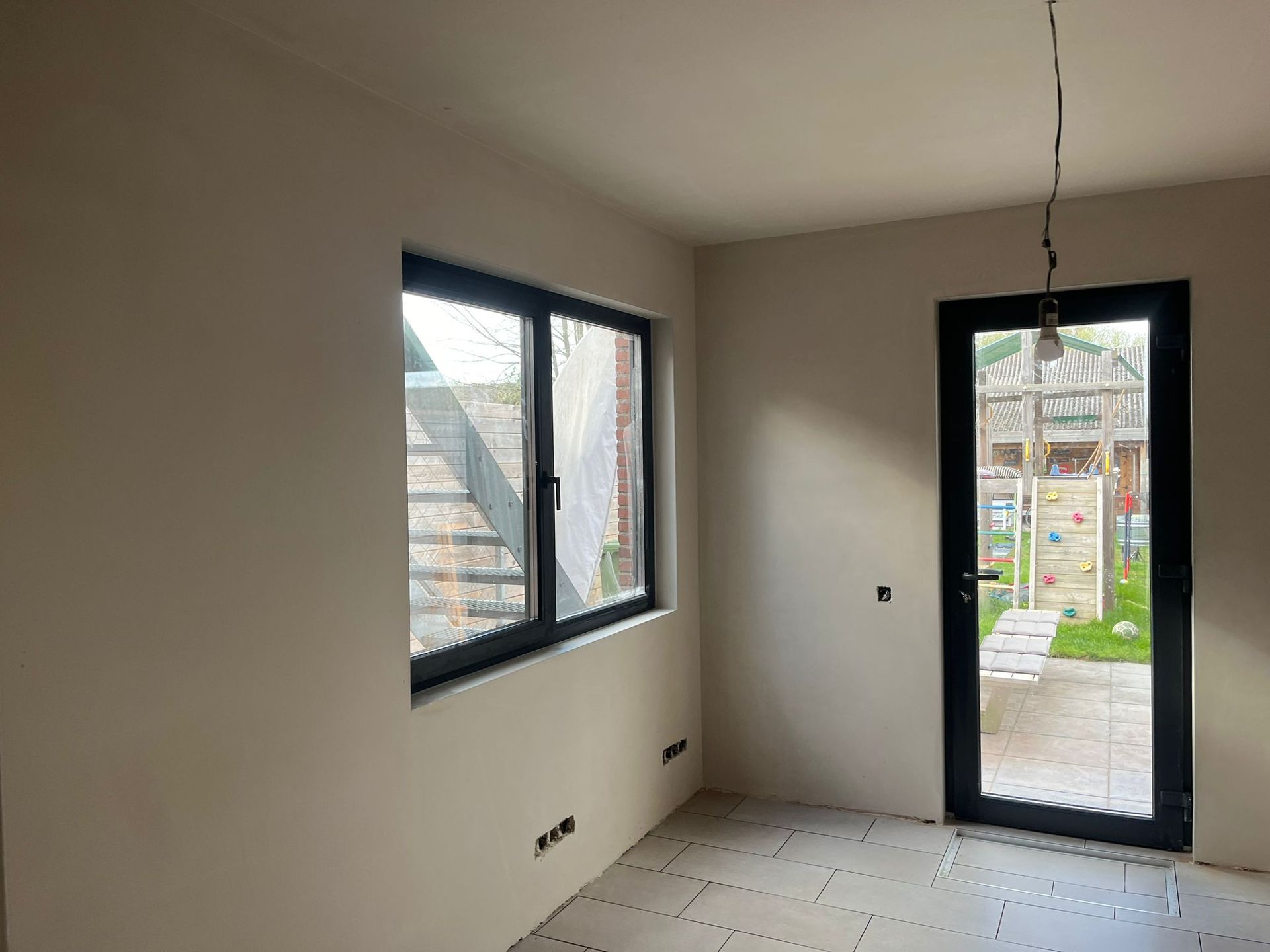 Een lege kamer met twee ramen en een deur.