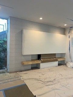 A modern white fireplace and built-in shelving with grey textured wall.