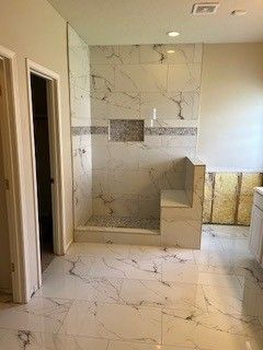 Bathroom with marble tile; shower with bench and built-in niche.
