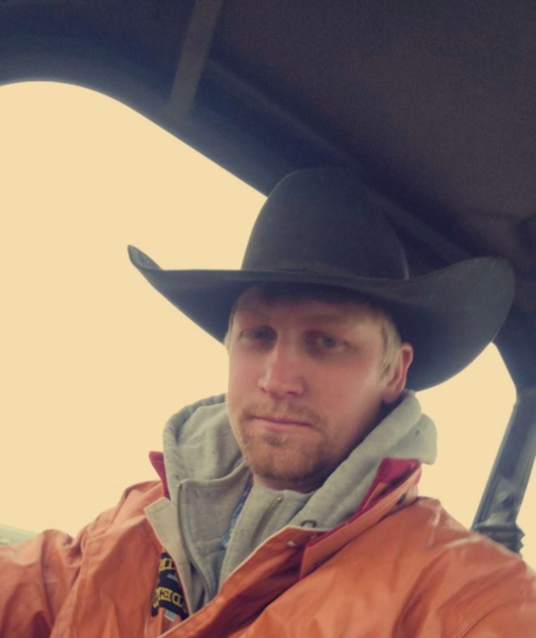 A man wearing a cowboy hat is sitting in a swather