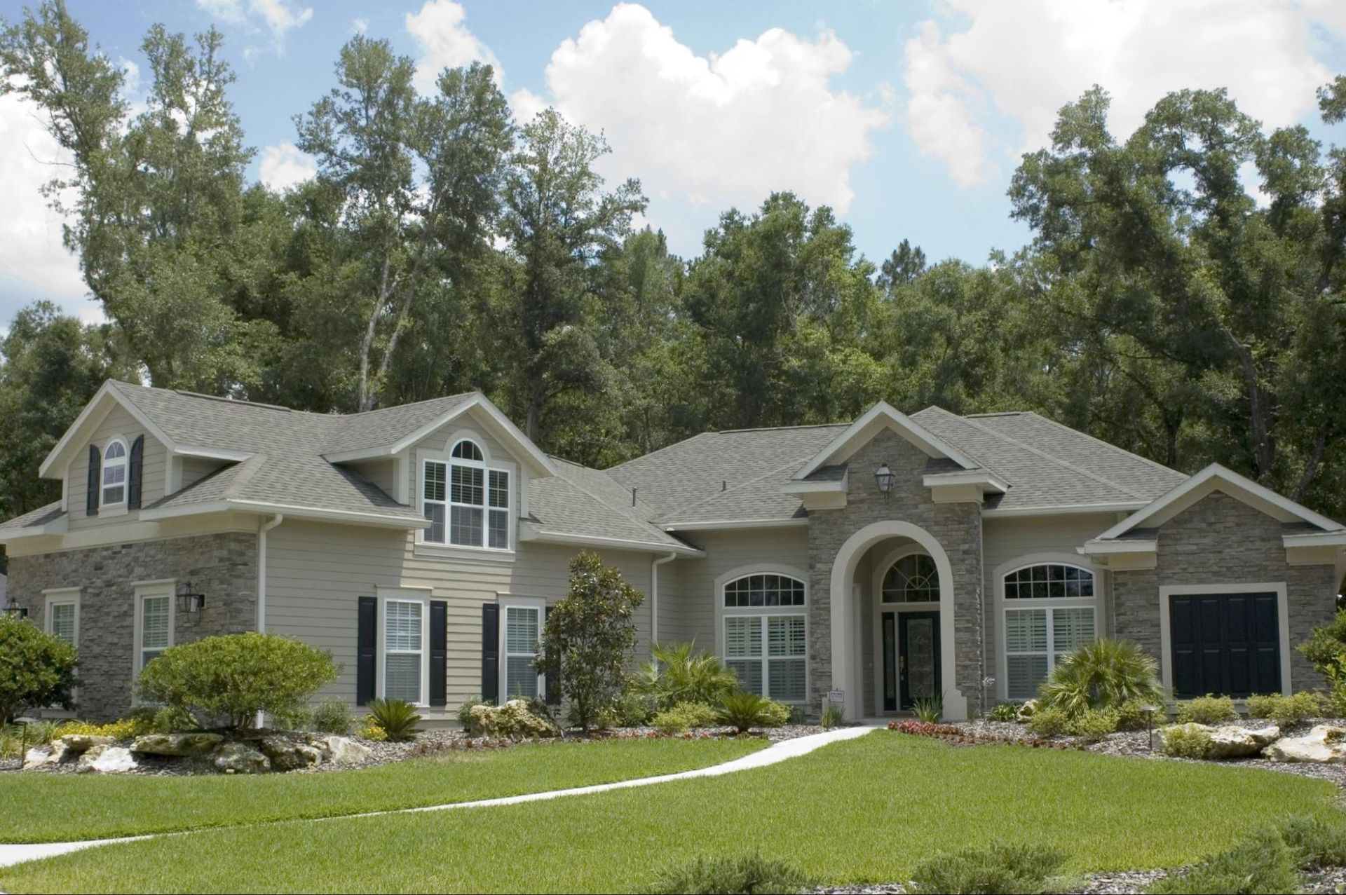 A large house with a gray roof is surrounded by trees