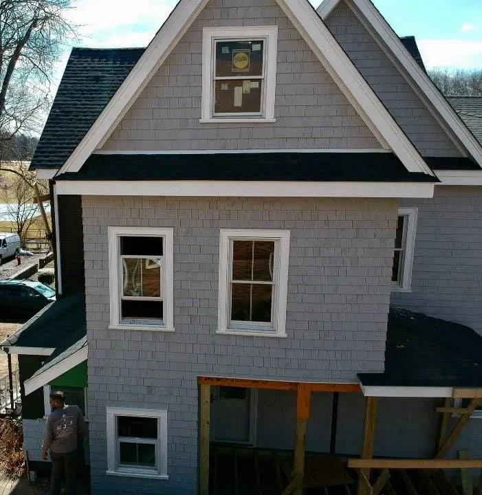 A gray house with a black roof is under construction