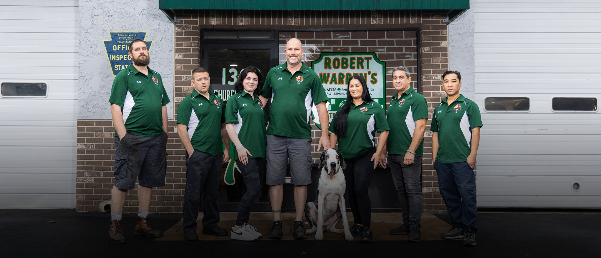Group of people in green shirts outside Robert A. Karron's garage, with a dog.