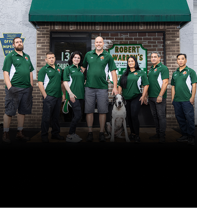 Group of people in green shirts outside a building with a dog, posing for a photo.