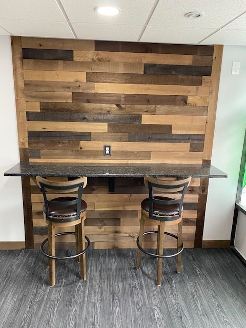 Bar area with wood plank wall, granite countertop, and two barstools.