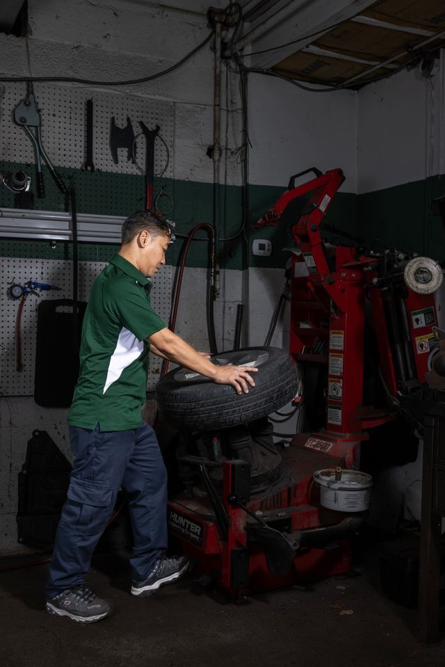 Mechanic placing a tire onto a tire changer in a garage.