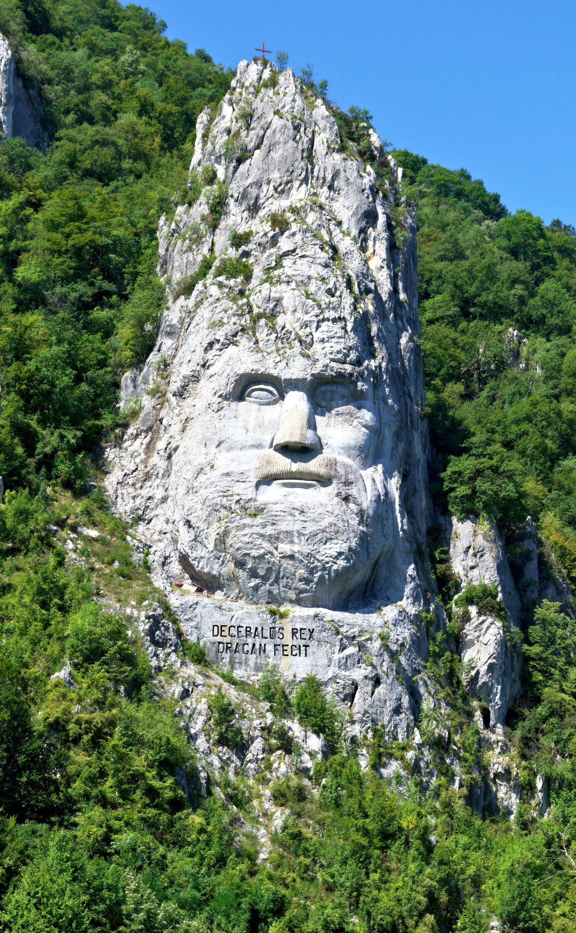 The rock sculpture of  Decebalus (Romanian: Chipul regelui dac Decebal) is a 42.9 m (141 ft) in height and 31.6 m (104 ft) in width carving in rock of the face of Decebalus (r. AD 87–106), the last king of Dacia, who fought against the Roman emperors Domitian and Trajan to preserve the independence of his country, which corresponded to modern Romania; it was made between 1994 and 2004, on a rocky outcrop on the river Danube, at the Iron Gates, and sets the world record for being the World's Largest rock sculpture on a river's bank, according to the World Record Academy. Photo: Yanko Malinov 