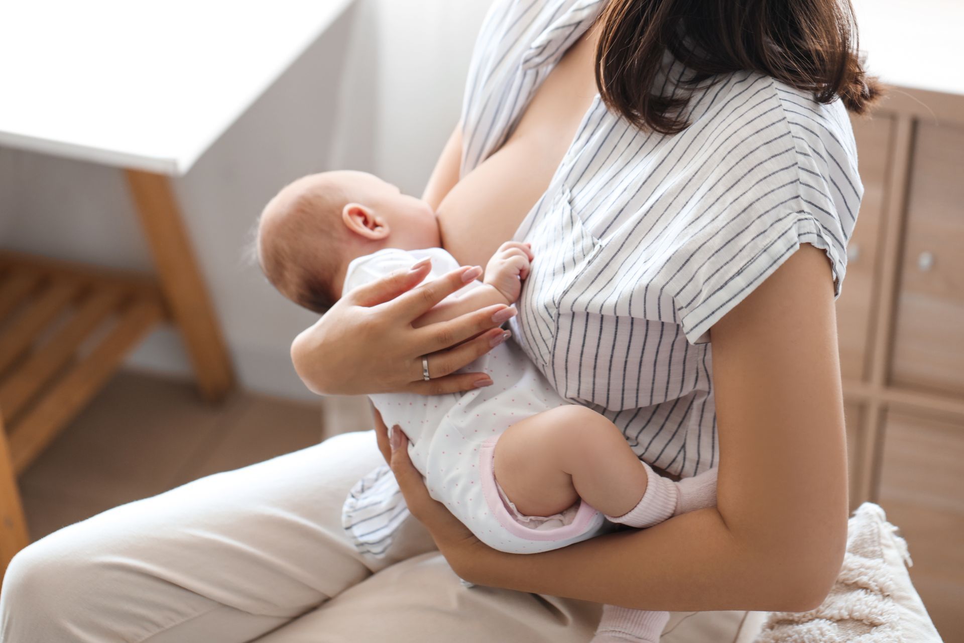 A woman is breastfeeding her baby while sitting on a couch.