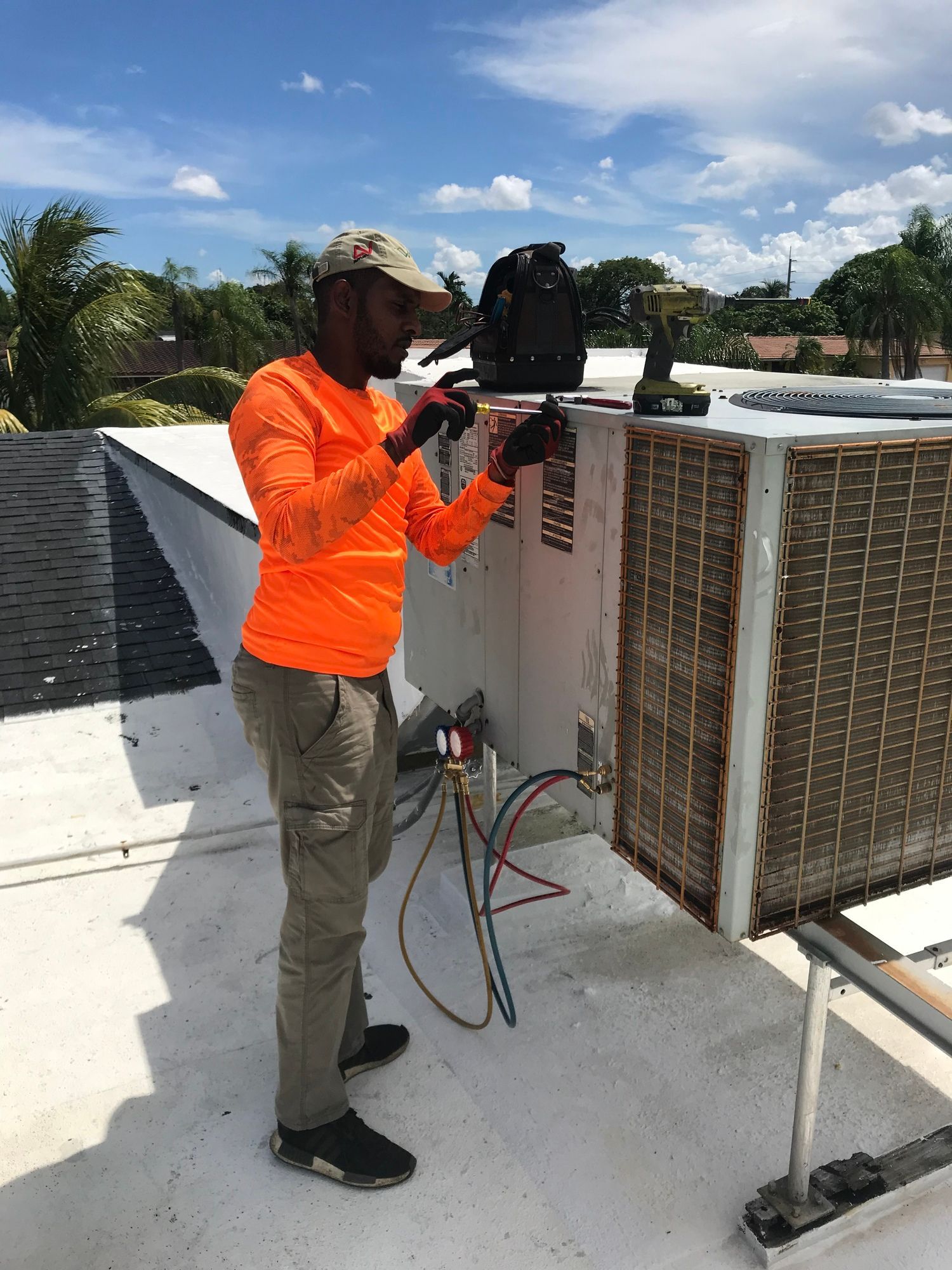 A man is working on an air conditioner on a roof.
