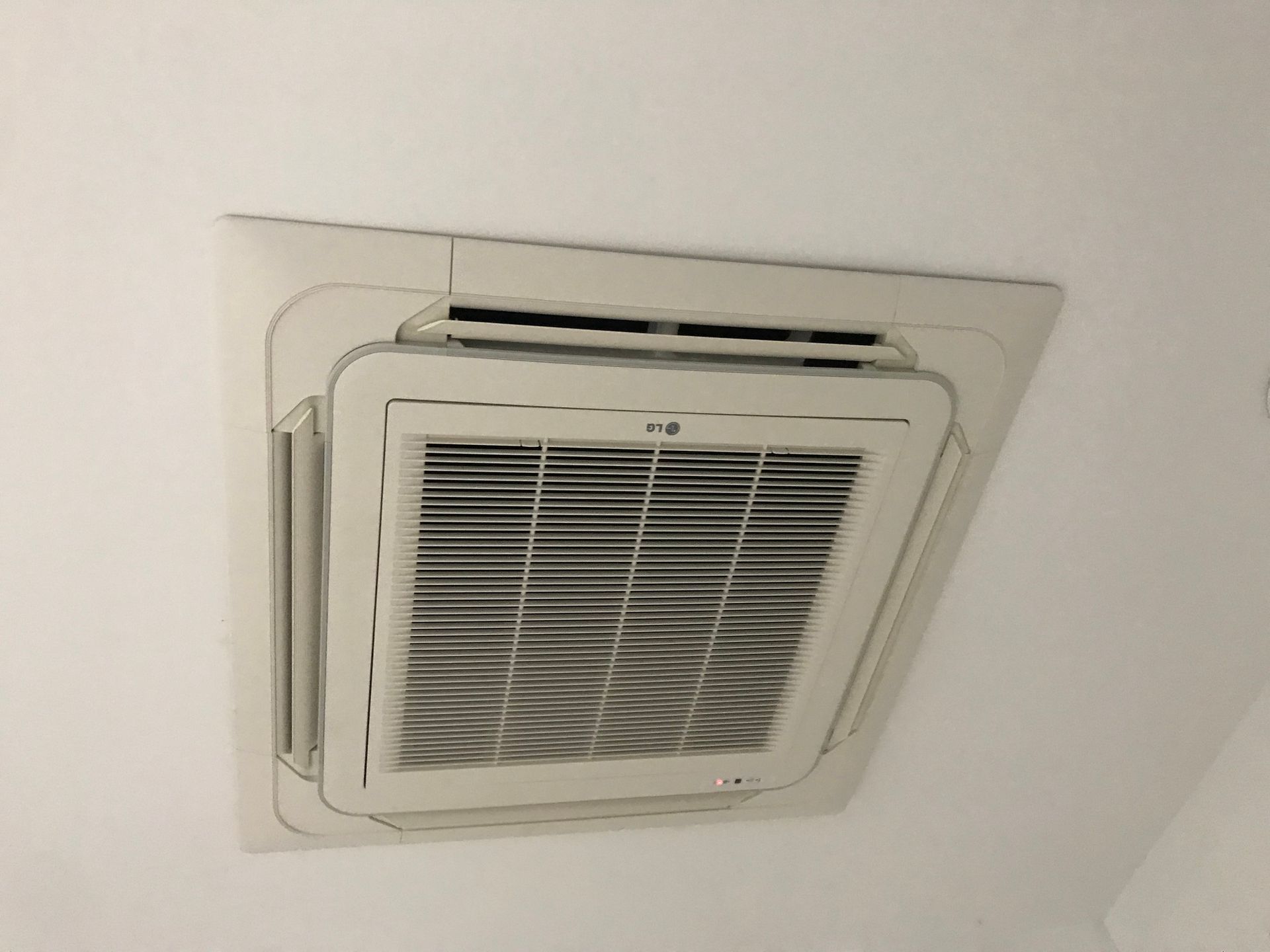A white air conditioner is hanging from the ceiling in a room.