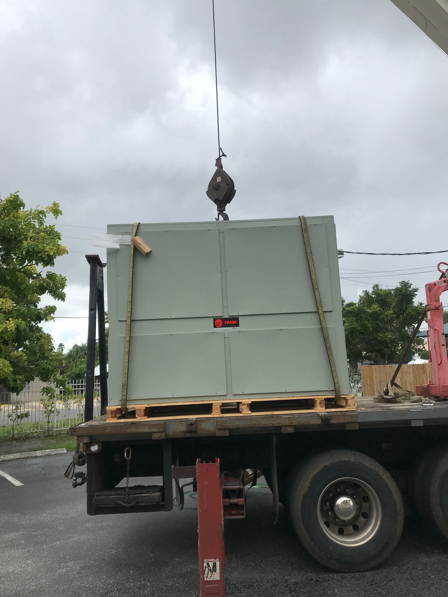 A truck is being lifted by a crane on a cloudy day.