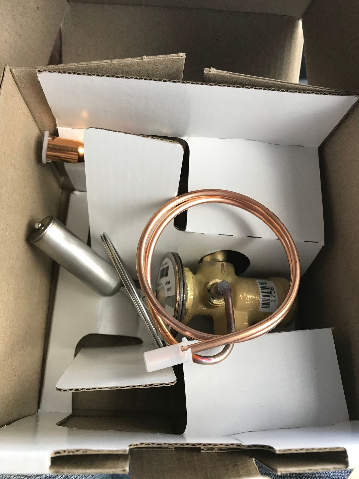 A copper pipe is sitting inside of a cardboard box.