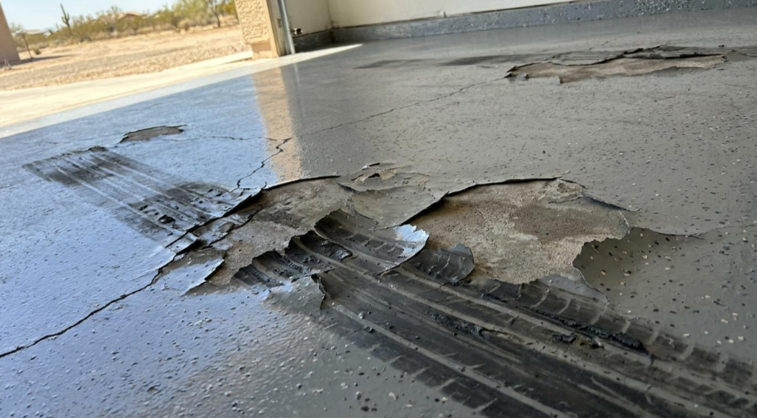 Cracked concrete floor with a large broken patch and water puddles in a garage or driveway
