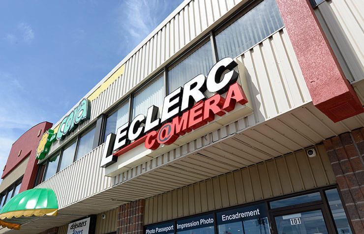 Enseigne Leclerc Commer sur une façade de magasin avec auvent rayé et façade en briques