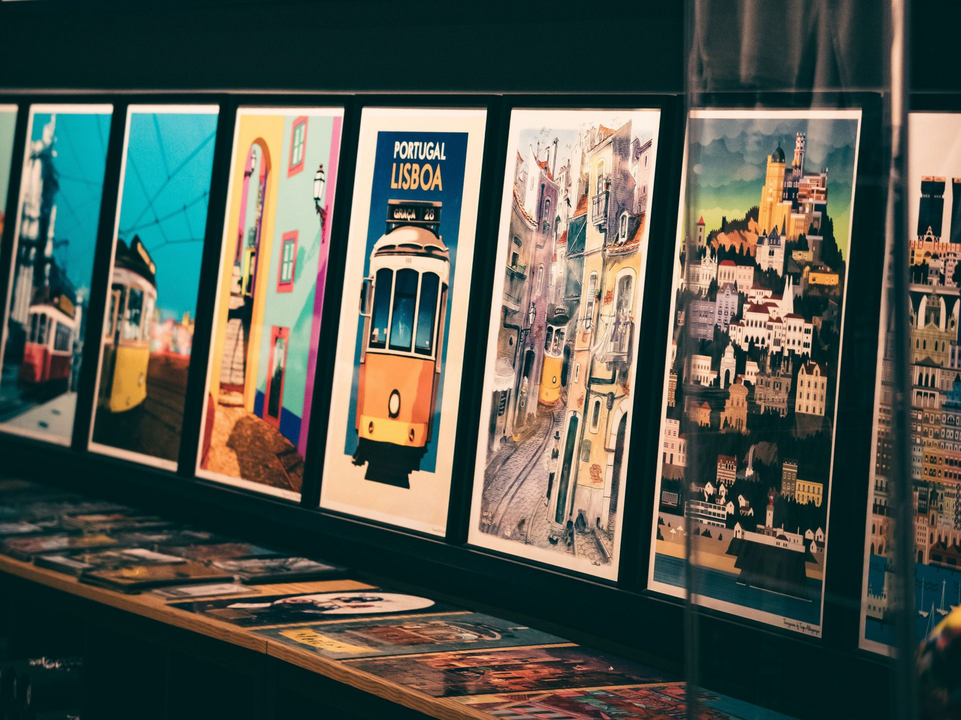 Des affiches de voyage encadrées, alignées sur un mur de galerie.