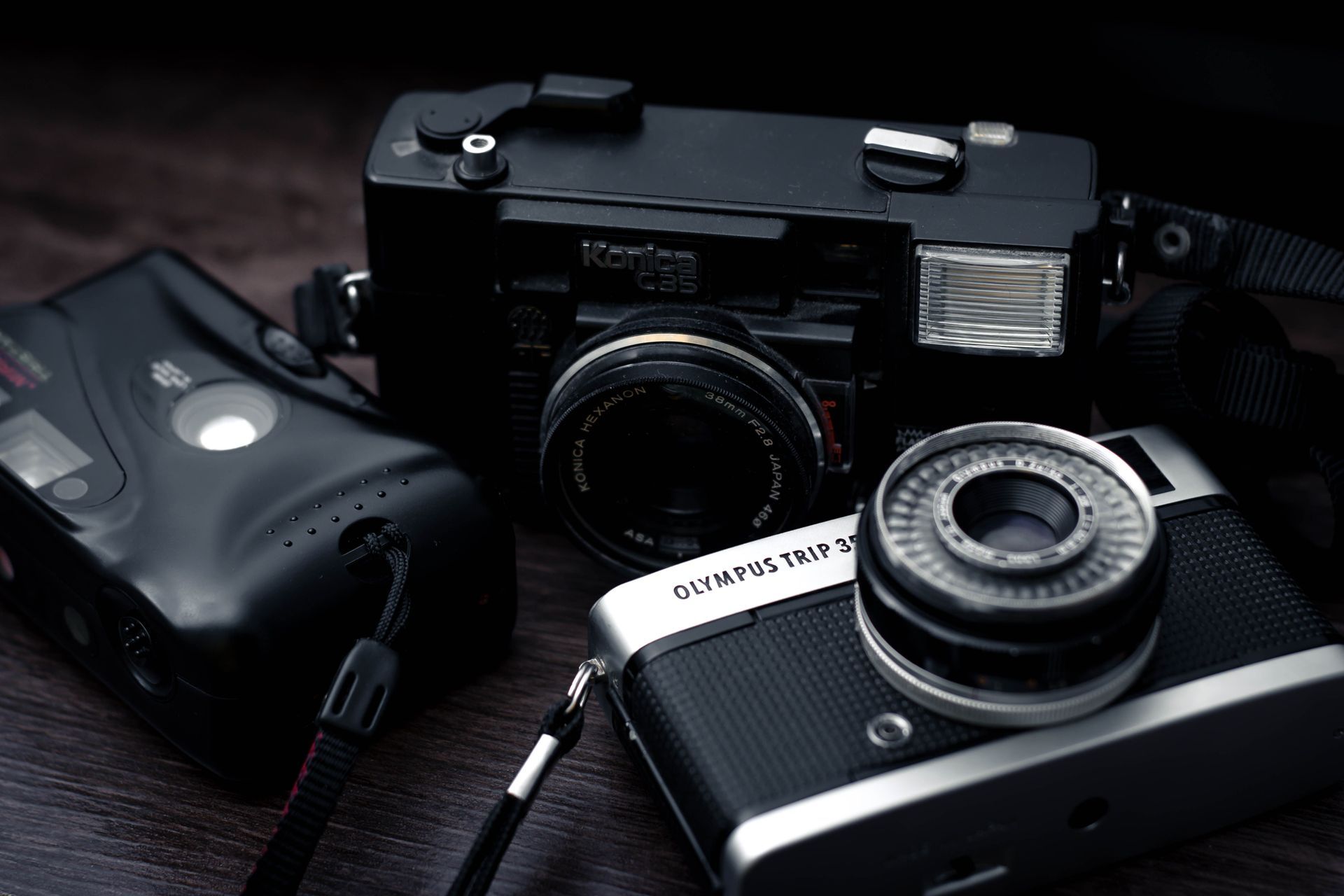 Trois appareils photo vintage et un flash sur une surface sombre
