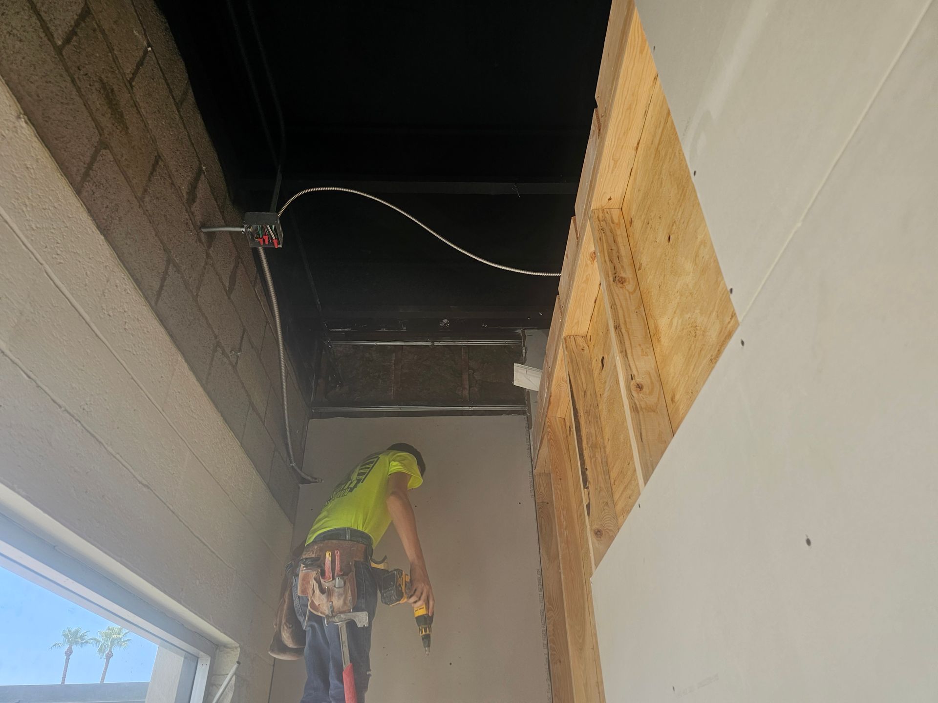 A man is working on a wall with a drill.