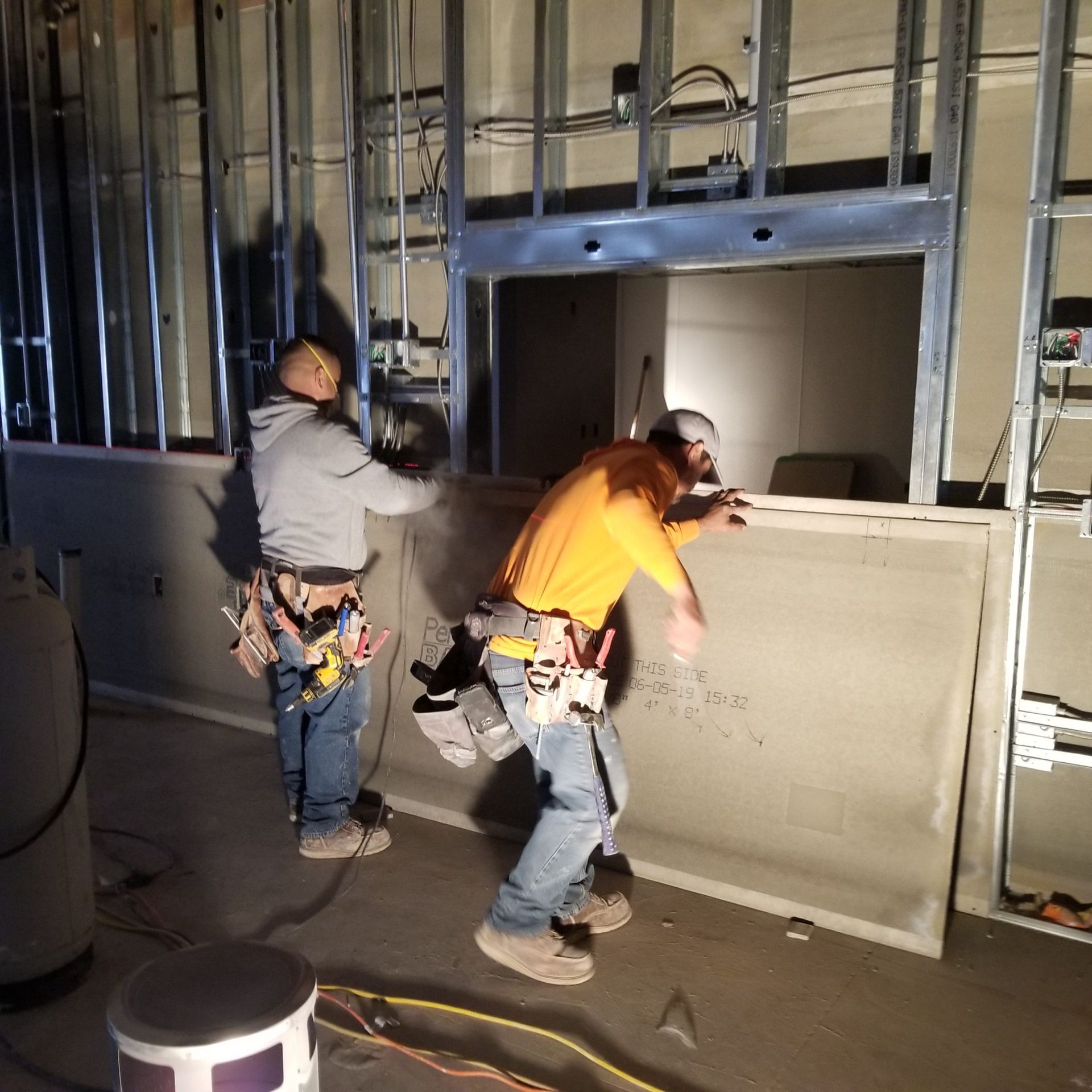 Two men are working on a wall in a dark room