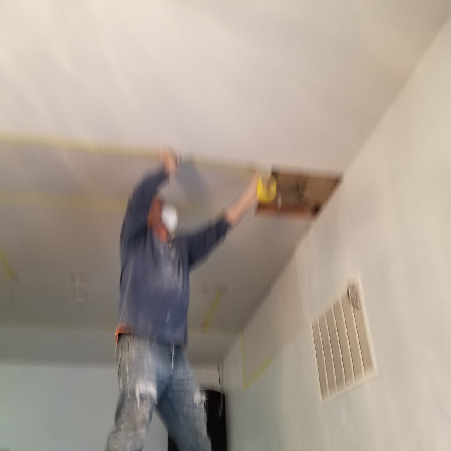 A man is painting the ceiling of a room with a spatula.