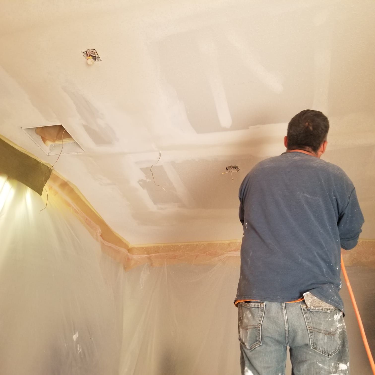 A man is painting the ceiling of a room.