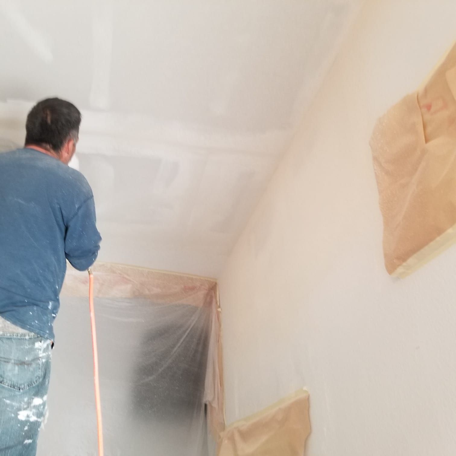 A man is standing in a room covered in plastic.