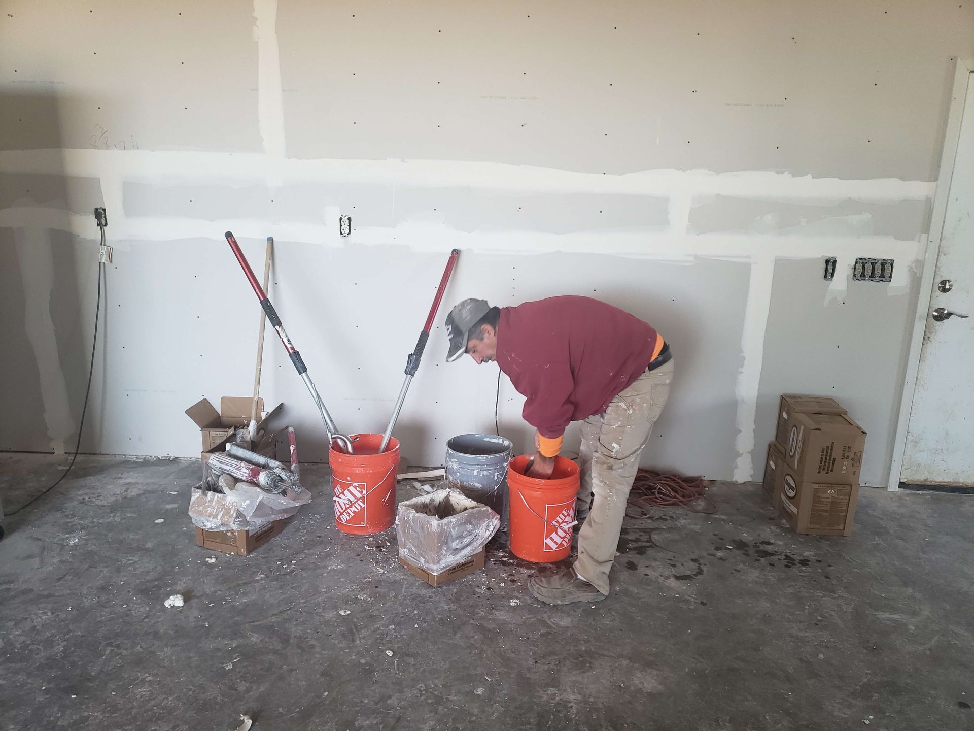 A man is working in a room with buckets of paint