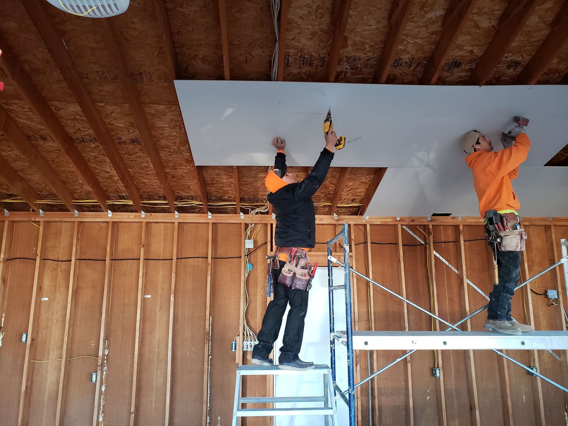 Two men are working on the ceiling of a building