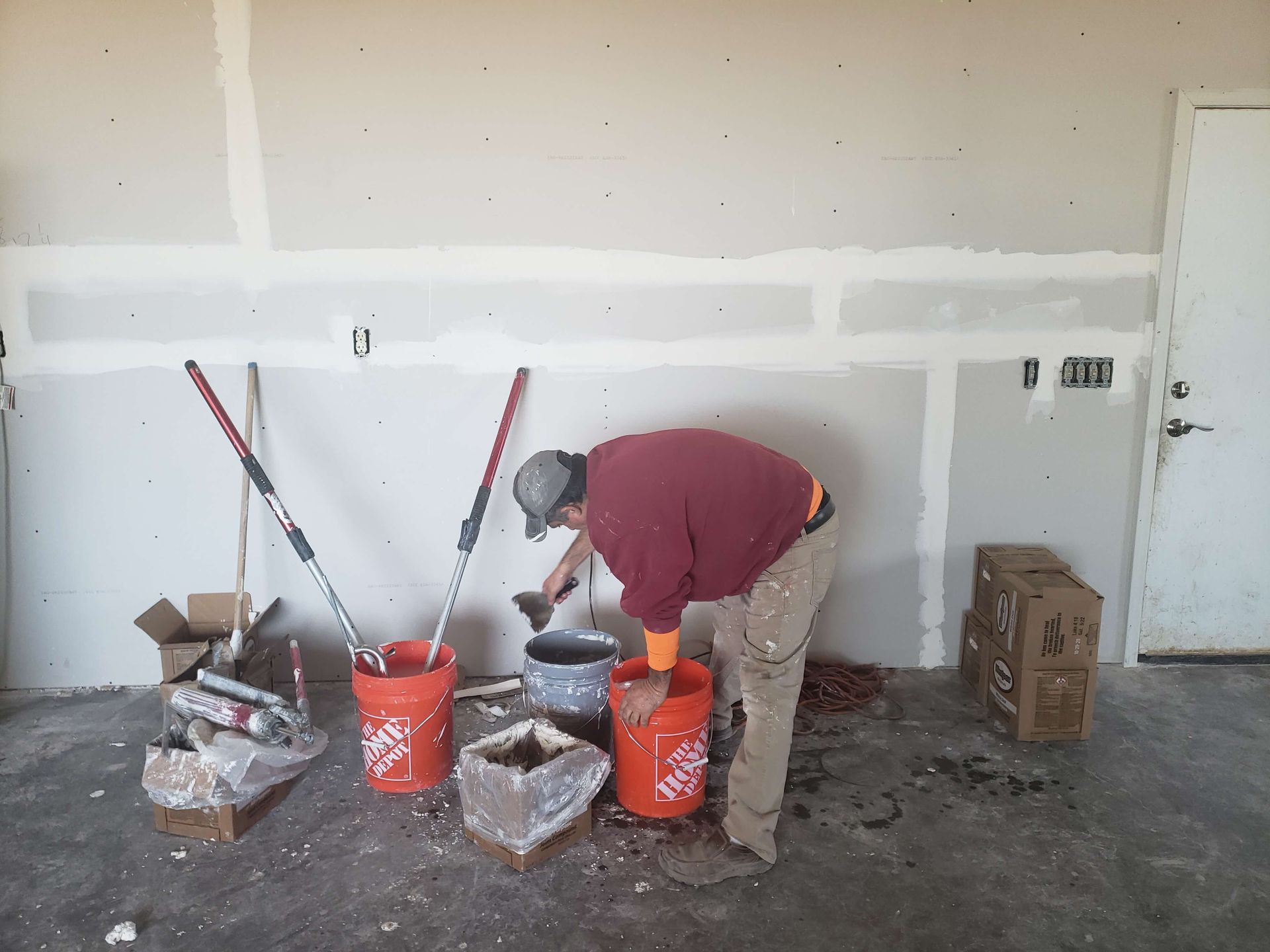 A man is working on a wall with buckets of home depot paint