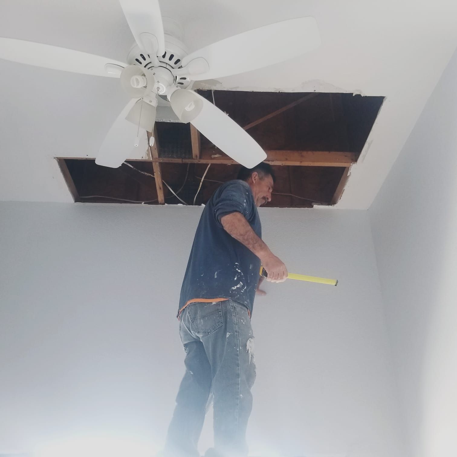 A man is measuring the ceiling with a tape measure
