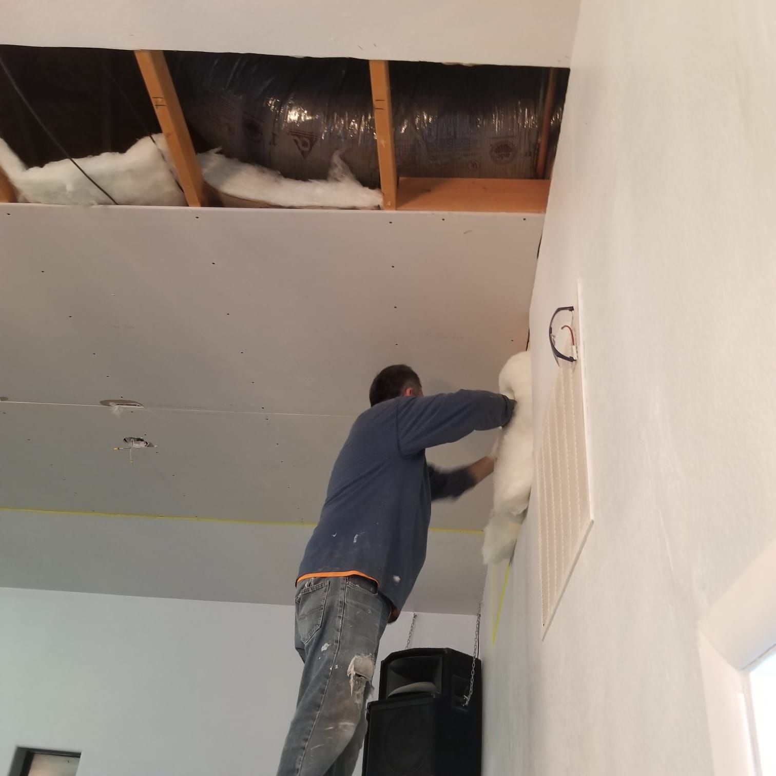 A man in a blue shirt is working on a ceiling