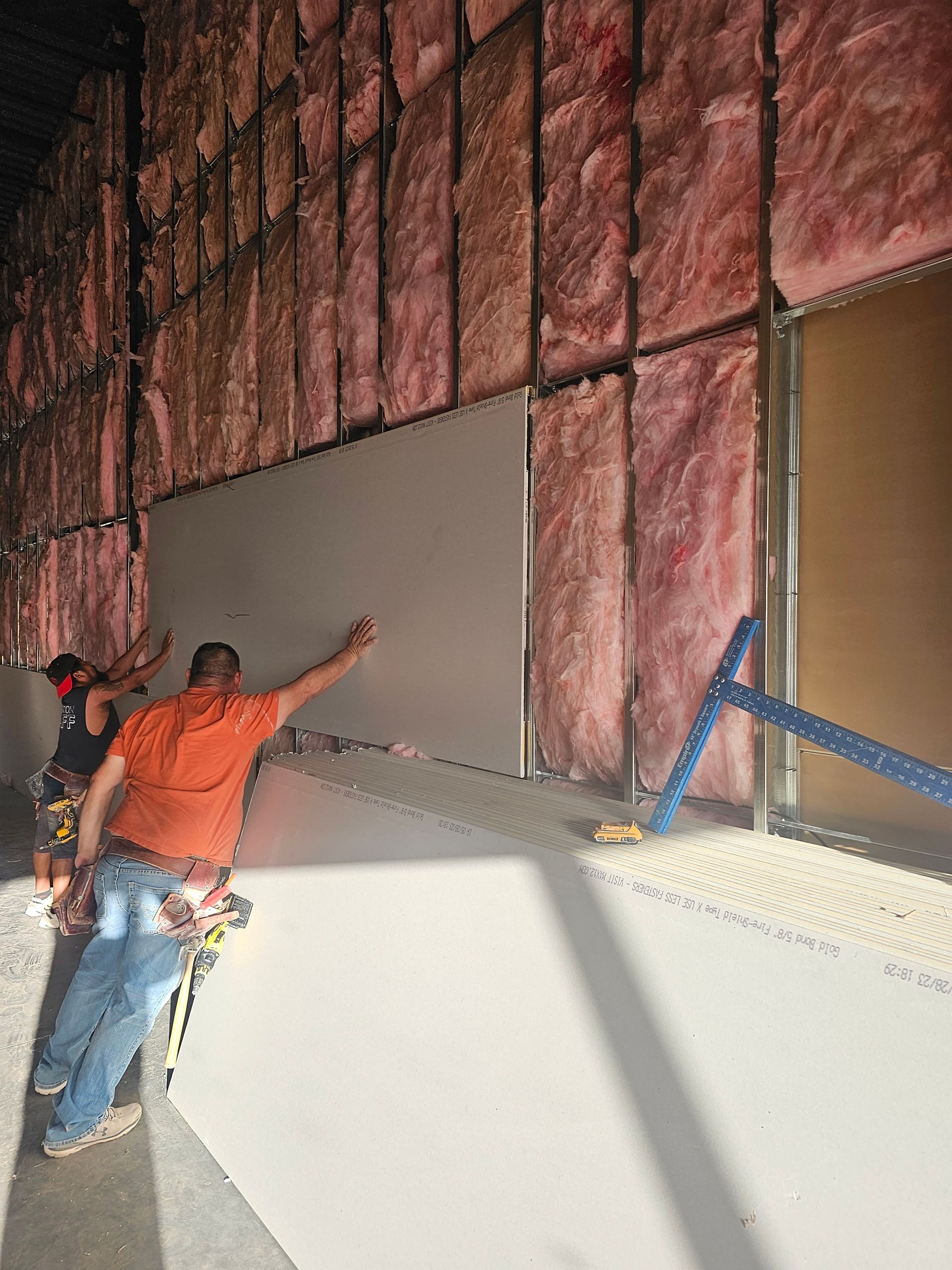 A man is standing in front of a wall with insulation on it.