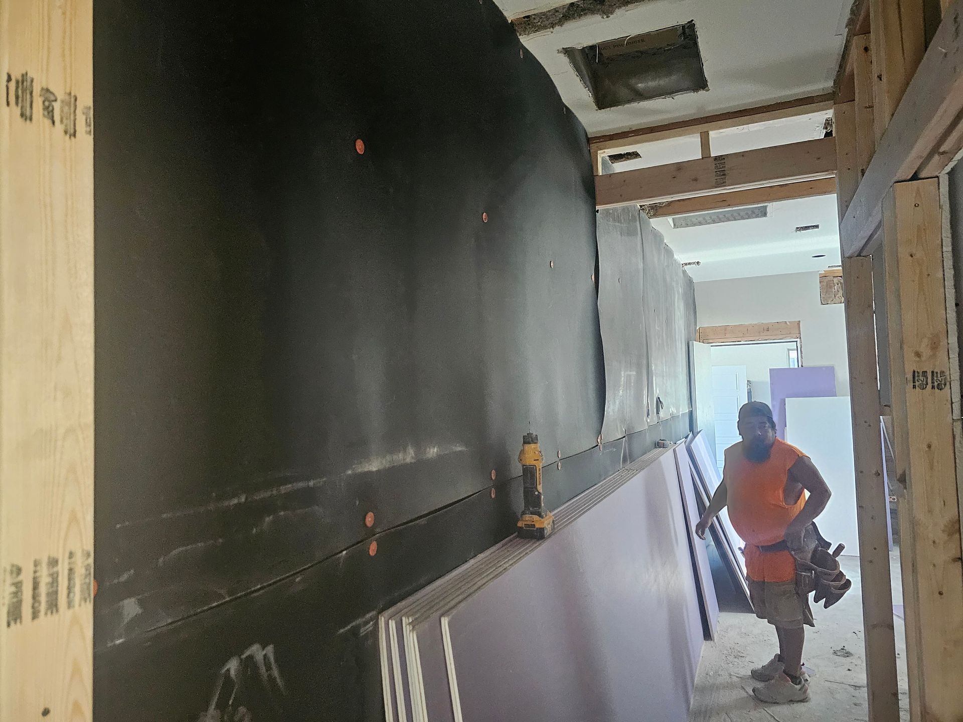 A man is standing in a hallway holding a piece of wood.