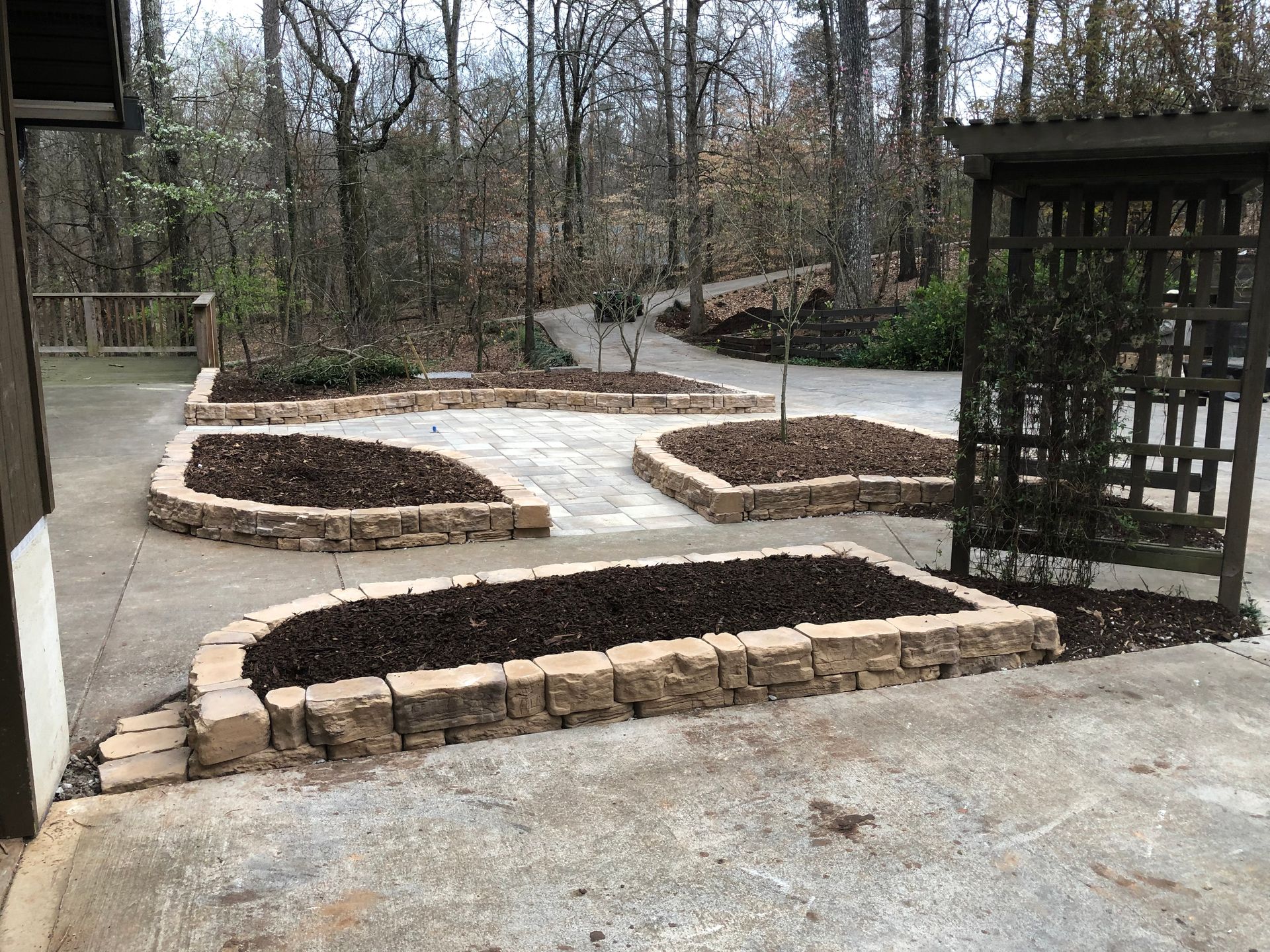 A patio with a lot of planters and trees in the background.