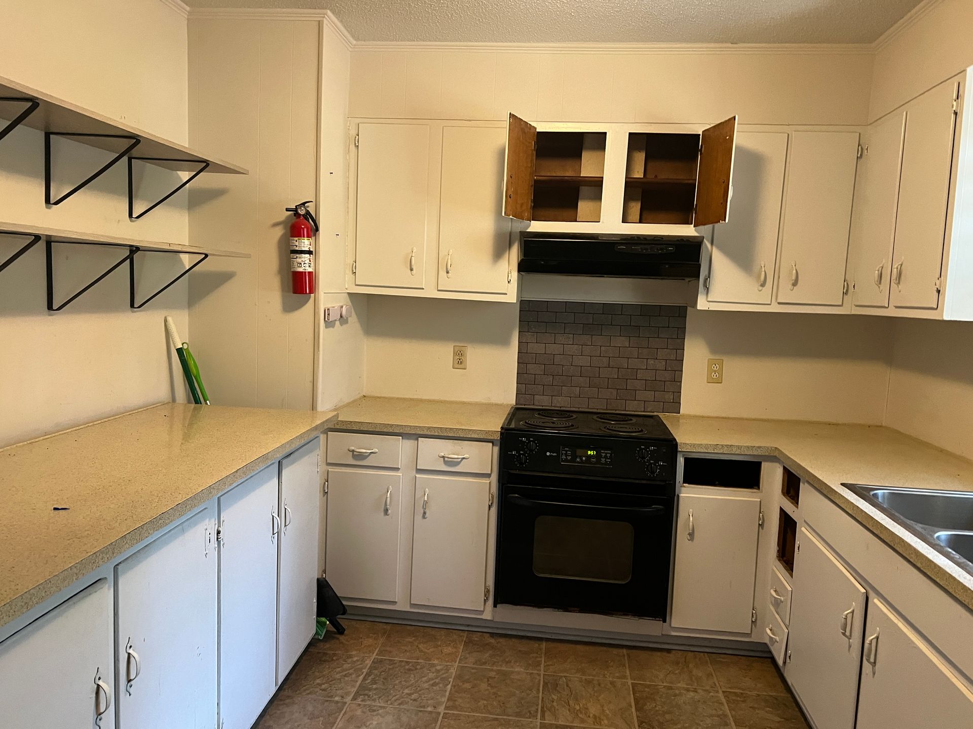 An empty kitchen with white cabinets and a black stove
