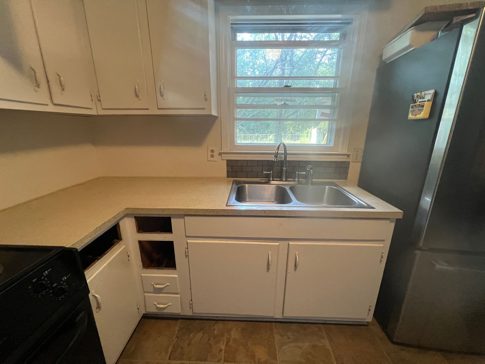 A kitchen with a sink , stove and refrigerator